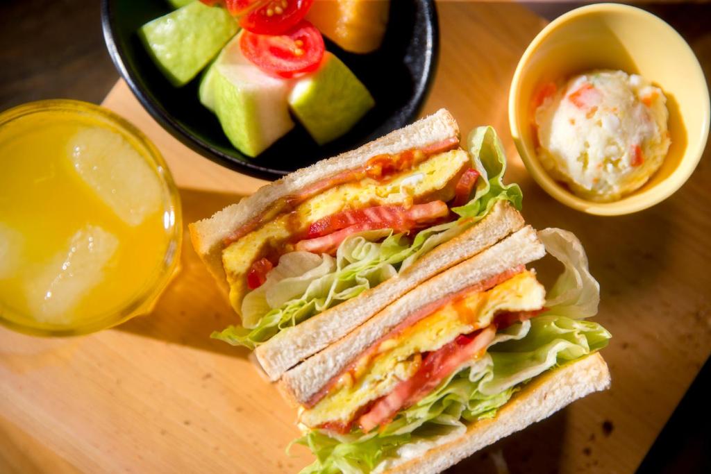 a sandwich on a table next to a bowl of fruit at Discovery B&amp;B in Linbian