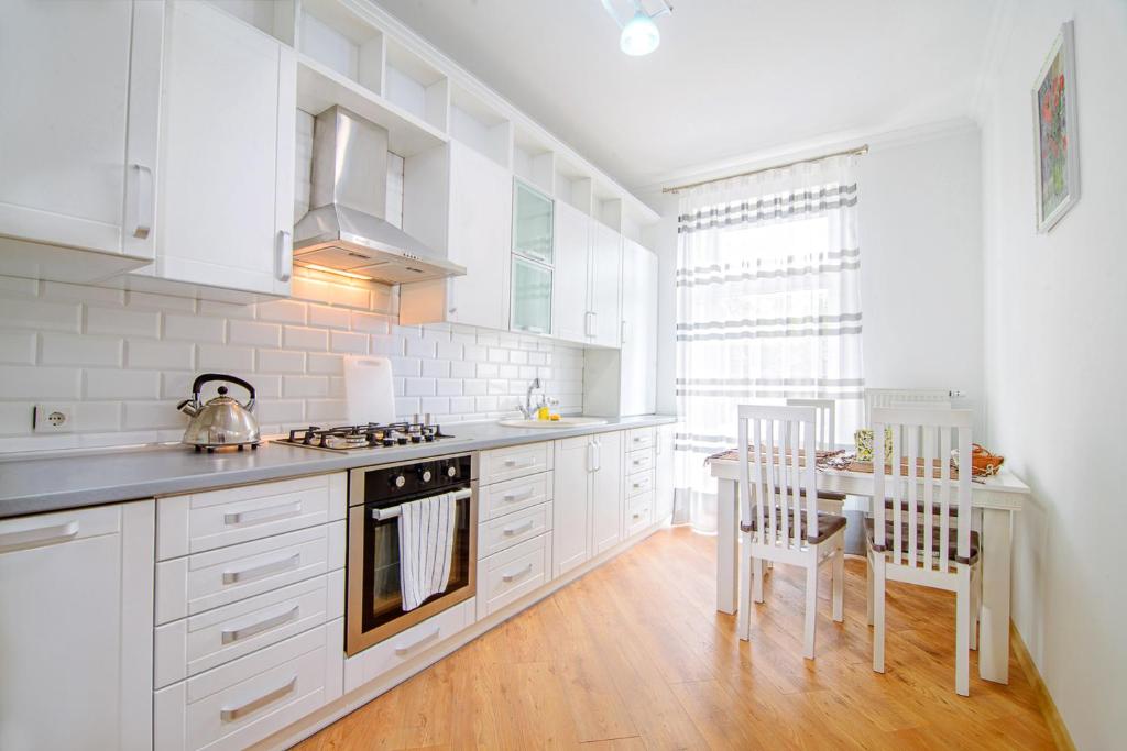 リヴィウにあるEnigma apartments Lychakivの白いキャビネット、テーブルと椅子付きのキッチンが備わります。