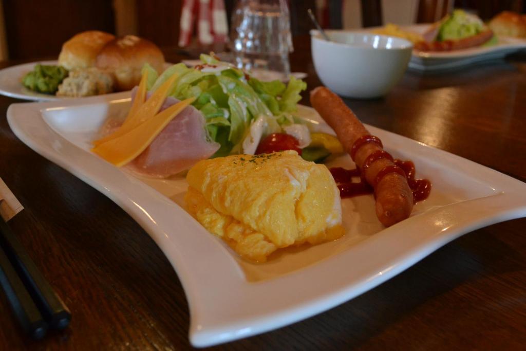 a white plate of food with a salad and sausage at Polan no Fue in Minamioguni