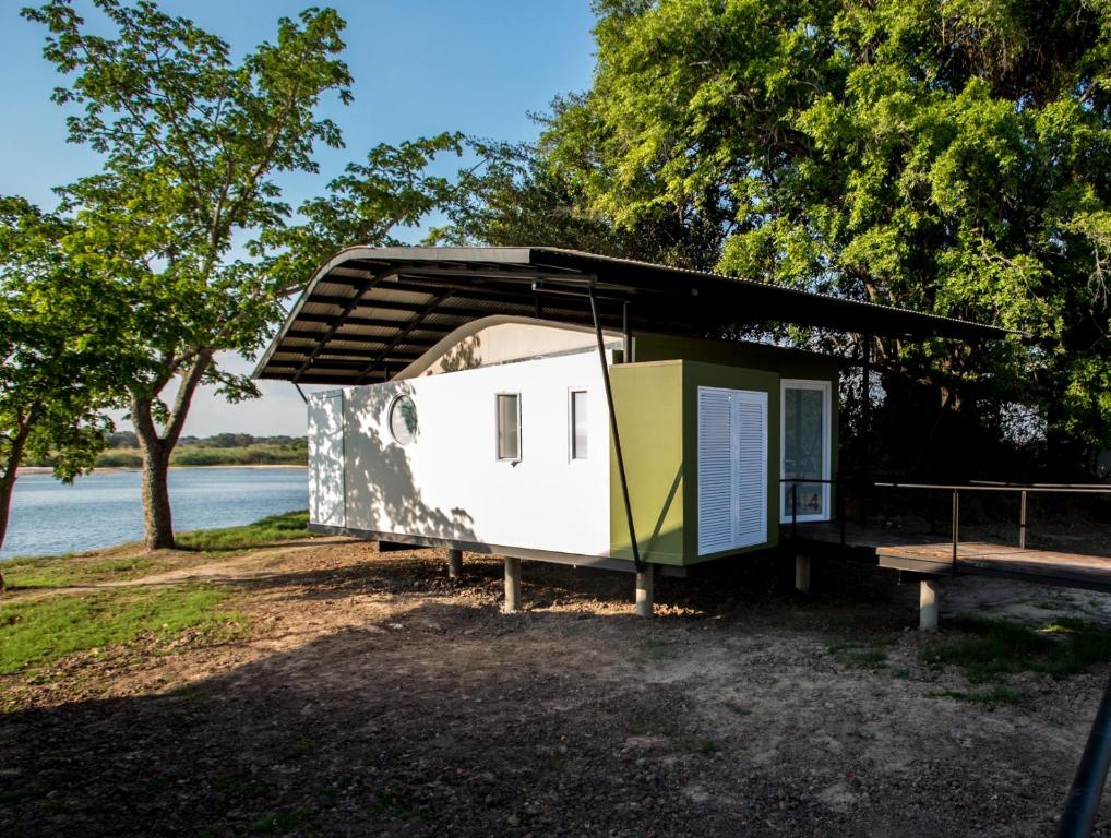 a tiny house with awning next to a lake at Zambezi Mubala Lodge in Katima Mulilo