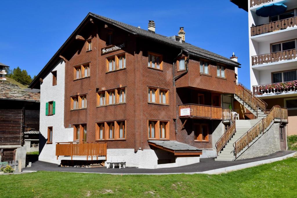 a large brick building with a balcony in front of a building at Sonnenhügel in Saas-Fee