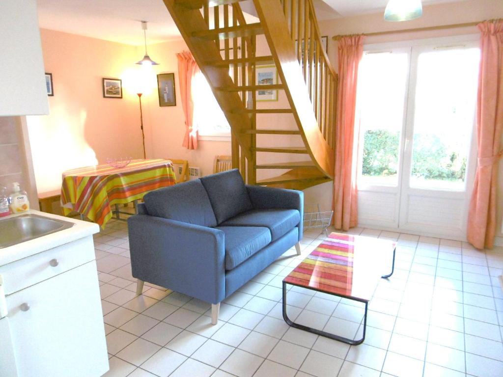 un salon avec une chaise bleue et un escalier dans l'établissement Maisonnette Urielle, à Saint-Gildas-de-Rhuys