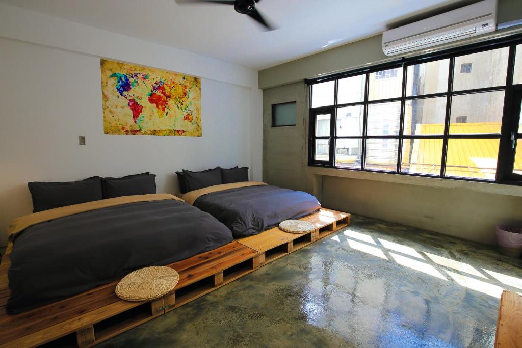 two beds sitting in a room with windows at it's Apt. in Tainan