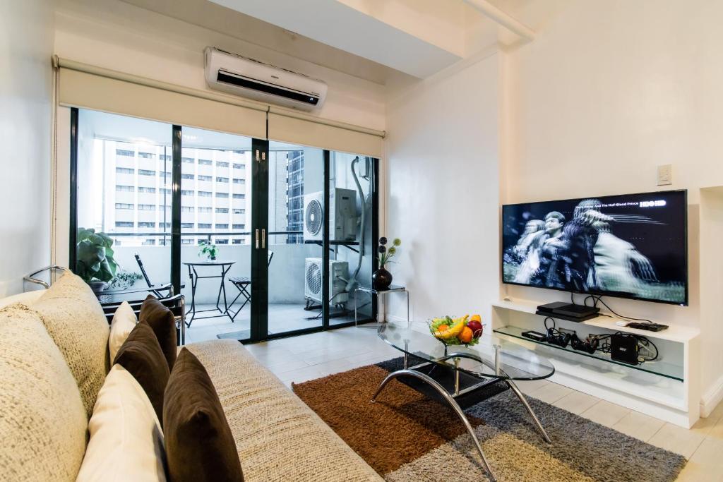 uma sala de estar com um sofá e uma televisão em Luxury spacious 2BR in Salcedo Village em Manila