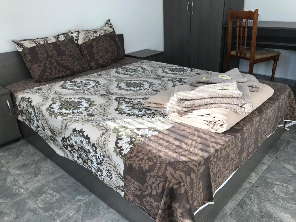 uma cama com um edredão com uma cadeira em Hotel Rositsa em Veliko Tŭrnovo