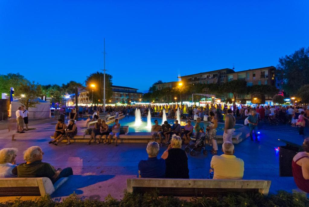 a crowd of people sitting around a fountain at night at Biloba in Bibione