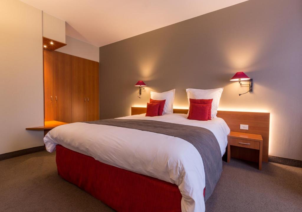 Cette chambre comprend un grand lit avec des oreillers rouges. dans l'établissement Hotel Royal, à La Panne
