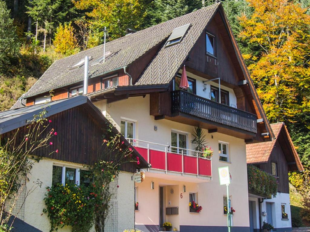 a large house with a red balcony and trees at Ferienwohnung am Hauskopf in Oppenau