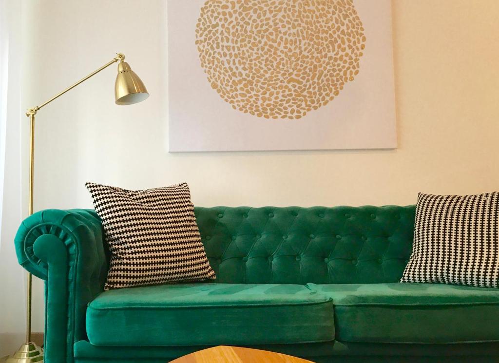 um sofá verde numa sala de estar com um candeeiro em Design apartment em Liepāja