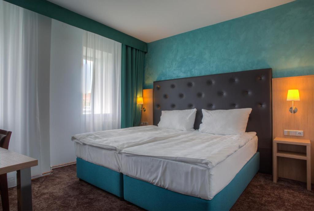 a bedroom with a large bed with a blue wall at Hotel Galatea in Mladá Boleslav