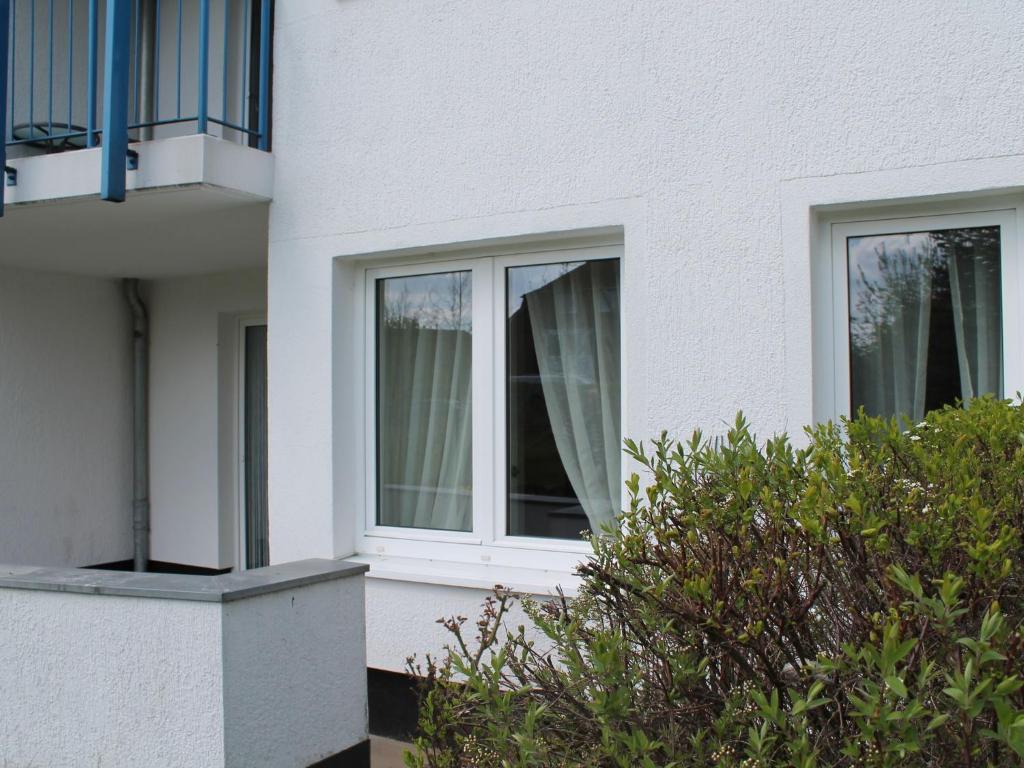 a white house with two windows and a bush at Bright Apartment in Boltenhagen near the Sea in Boltenhagen