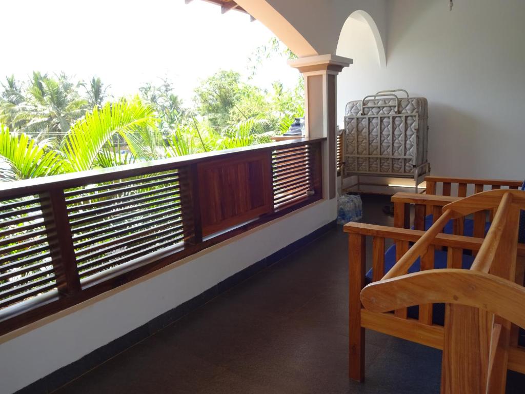 a balcony with a wooden railing and a wooden chair at Dunhill Beach Resort in Agonda