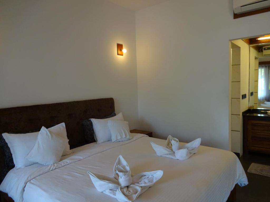 a bedroom with two beds with white towels on them at Dunhill Beach Resort in Agonda