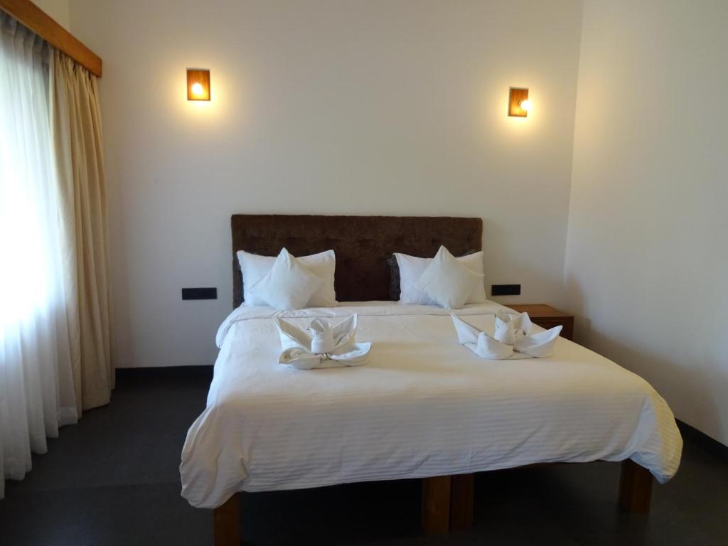 a bedroom with a white bed with two white bows on it at Dunhill Beach Resort in Agonda