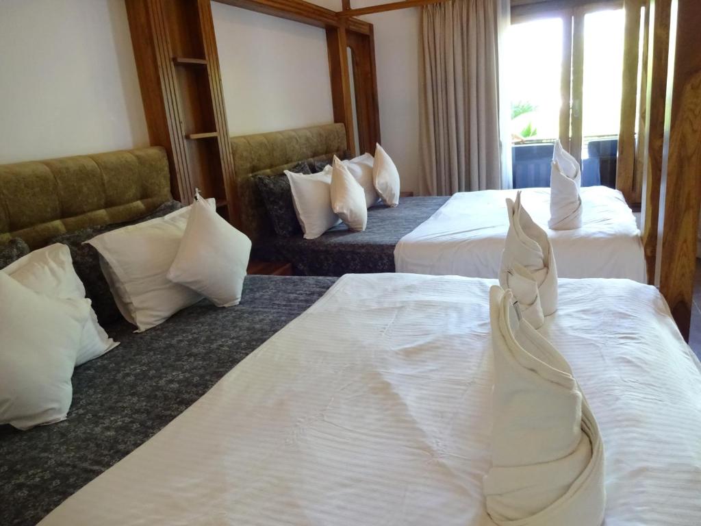 a hotel room with three beds with white sheets at Dunhill Beach Resort in Agonda