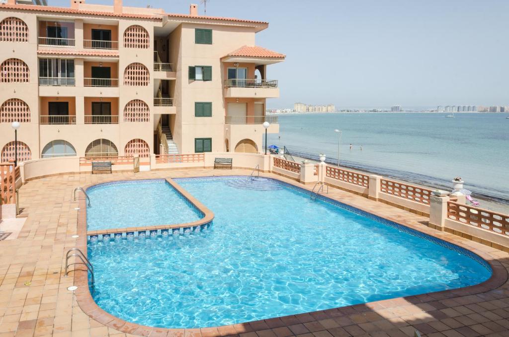 einem Pool vor einem Gebäude am Meer in der Unterkunft Apartamentos Zambra III in La Manga del Mar Menor