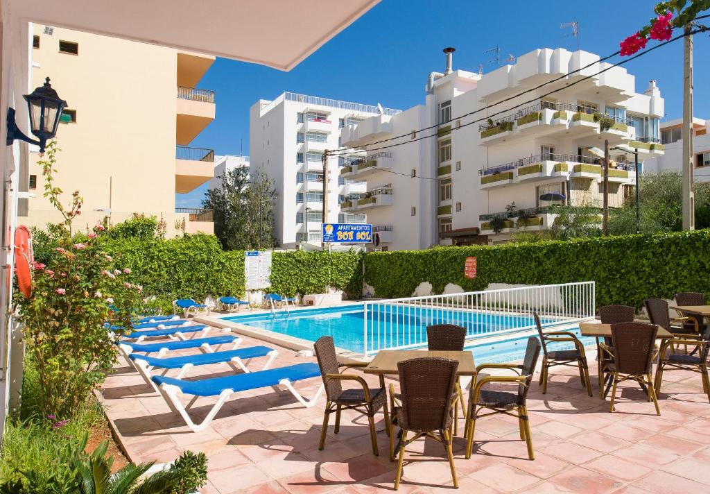 una piscina con mesas y sillas junto a un edificio en Apartamentos Green Line Bon Sol - AB Group, en Playa d'en Bossa