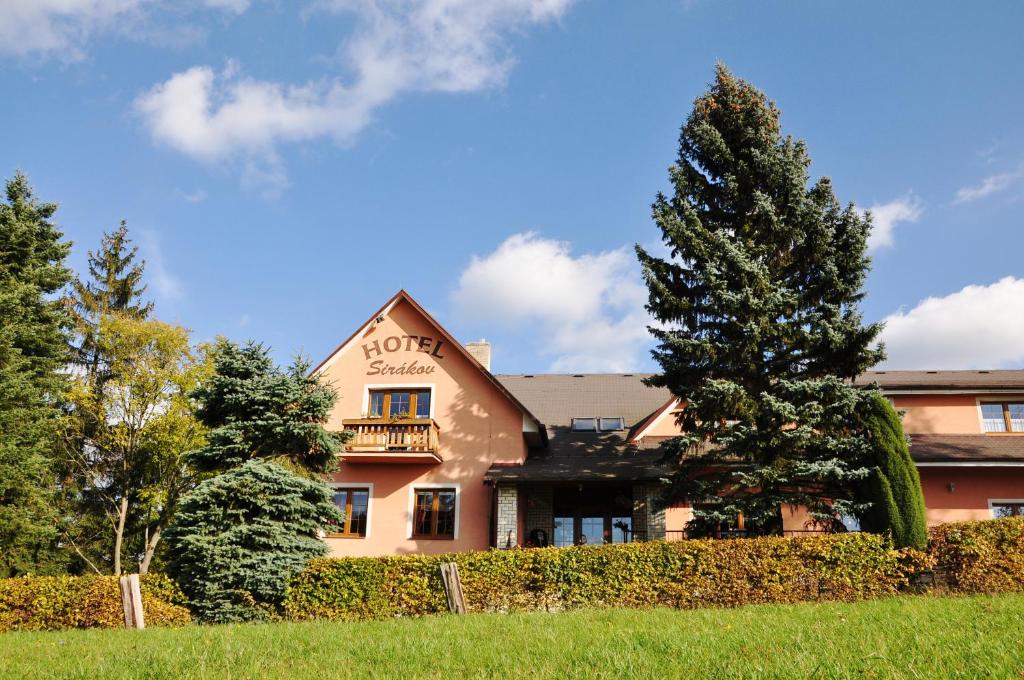 a building with a fence and a tree at Hotel Sirákov in Liptál