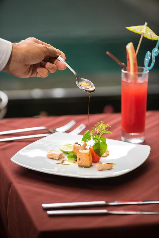 a person is pouring sauce on a plate of food at Vihara The City of Temples in Siem Reap