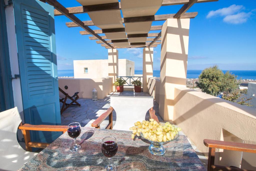 a table with wine glasses and fruit on a balcony at Anemoessa Villa in Oia
