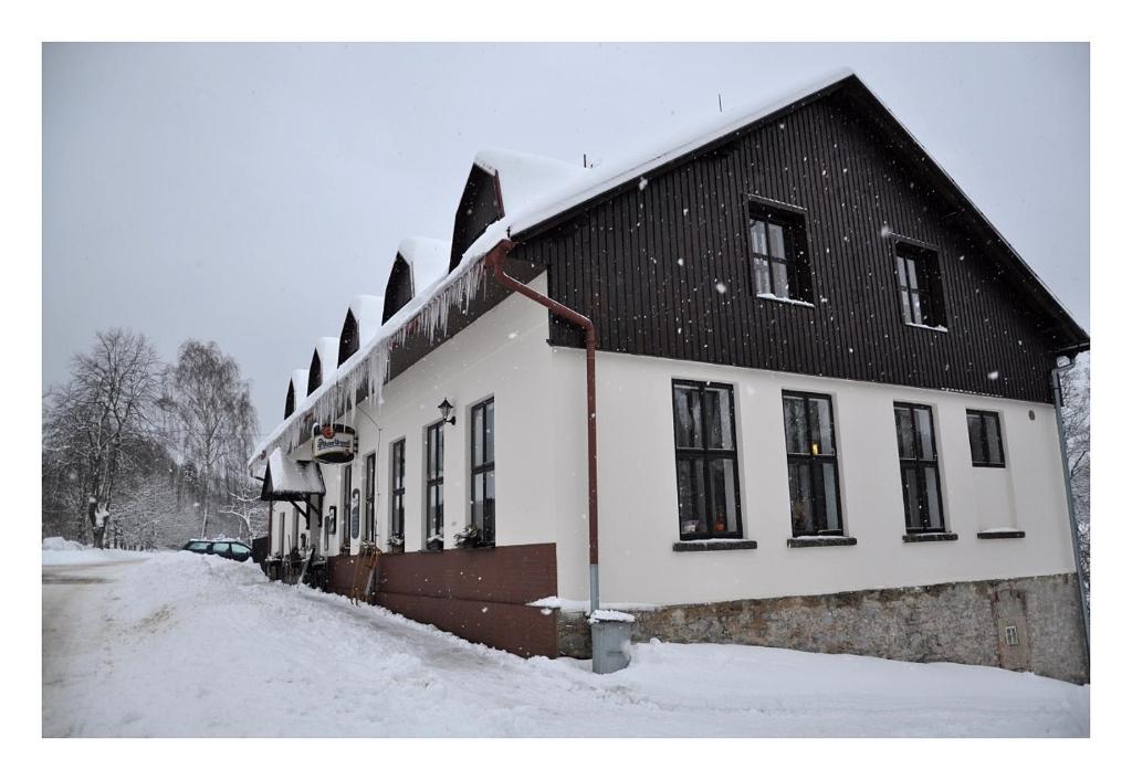 a building with a black roof in the snow at Penzion Severák in Rokytnice v Orlických Horách