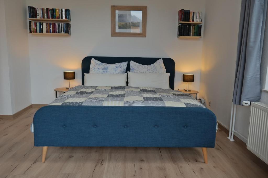 uma cama azul num quarto com 2 candeeiros em Ferienwohnung Wartburgblick em Eisenach
