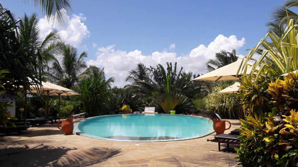 
a swimming pool with a beach chair and palm trees at African Dream Cottages - Diani Beach in Diani Beach
