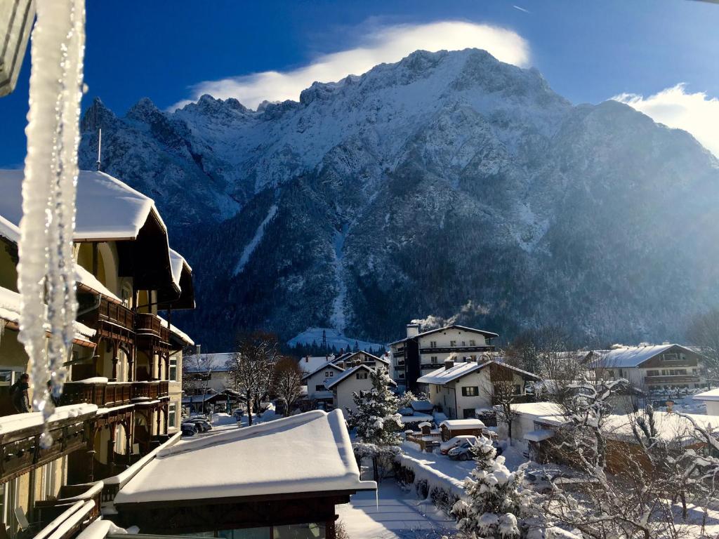 a snow covered mountain in front of a town with houses at Post-Hotel in Mittenwald