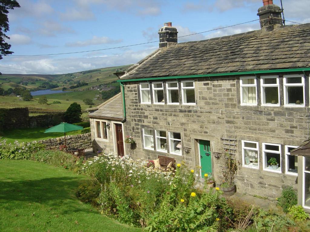 a stone house with a green door in a field at Royds Hall Cottage in Keighley