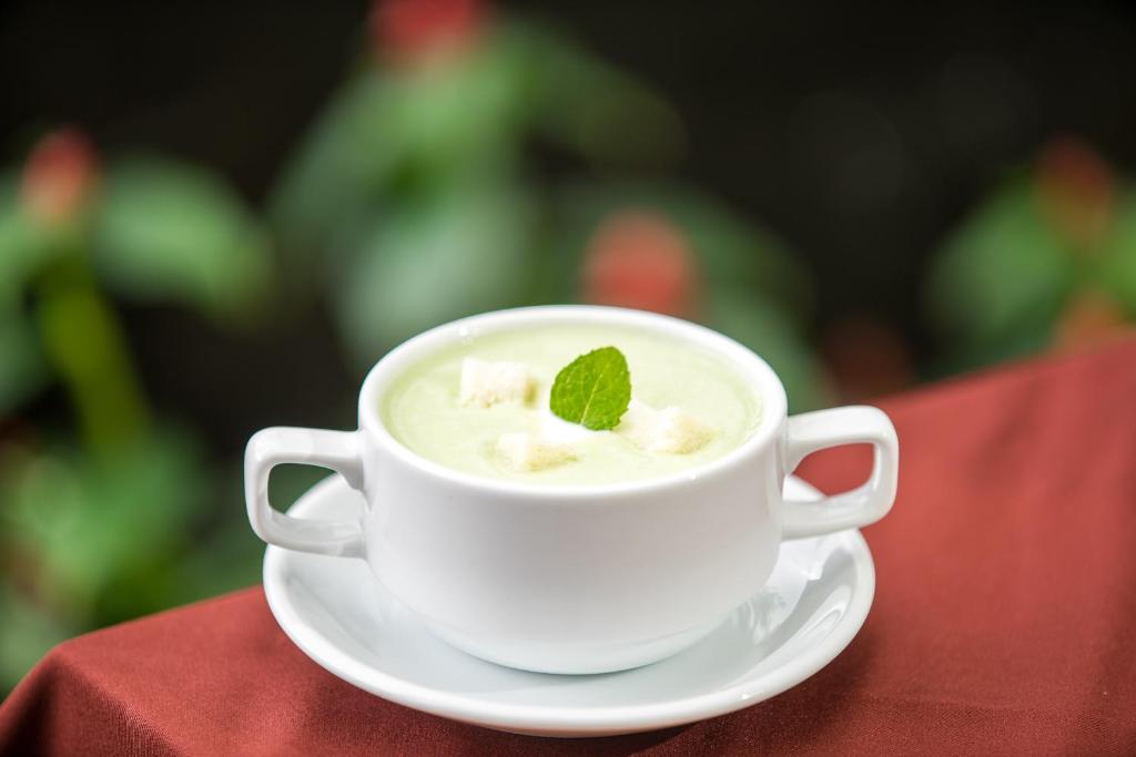 a white cup of coffee with a mint leaf on top at Vihara The City of Temples in Siem Reap