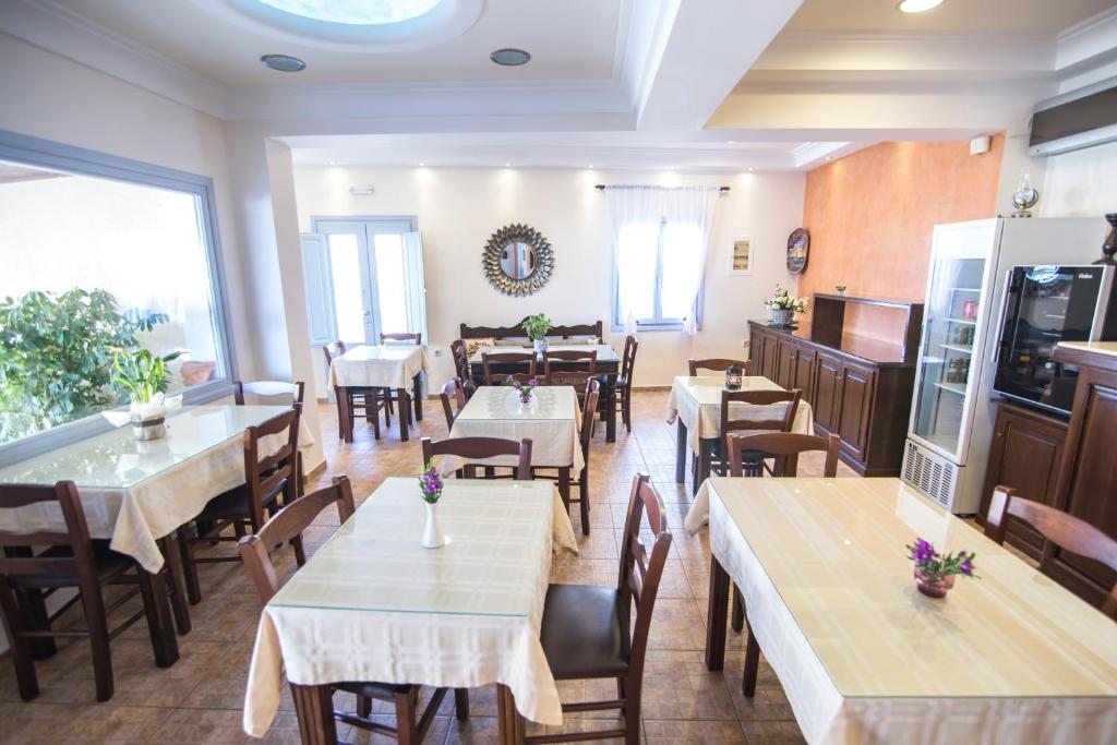 a restaurant with tables and chairs and a room with windows at Anemoessa Villa in Oia