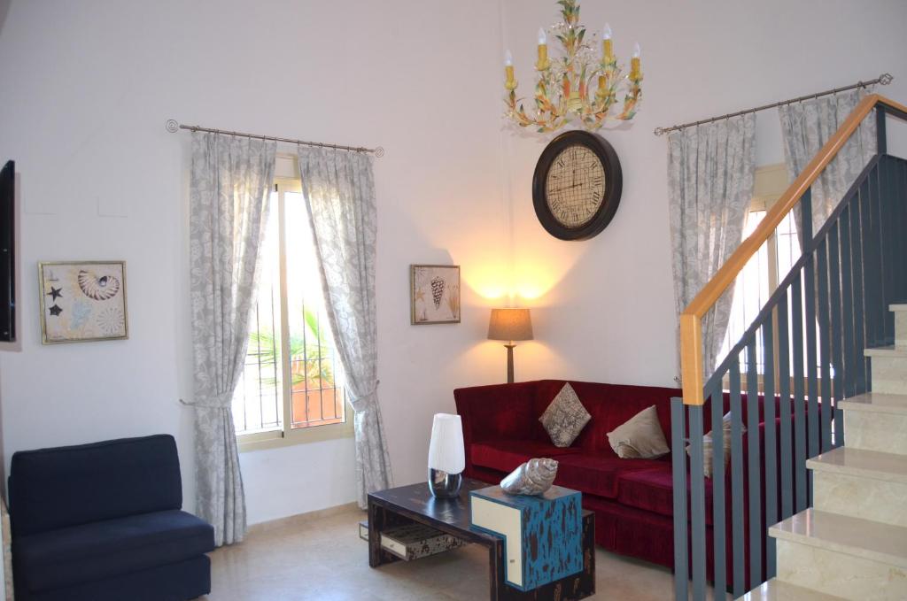 a living room with a red couch and a clock on the wall at Villa Aznalcazar in Sanlúcar la Mayor