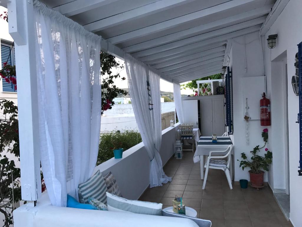 a porch with white curtains and a table and chairs at Morpheus Rooms in Kini