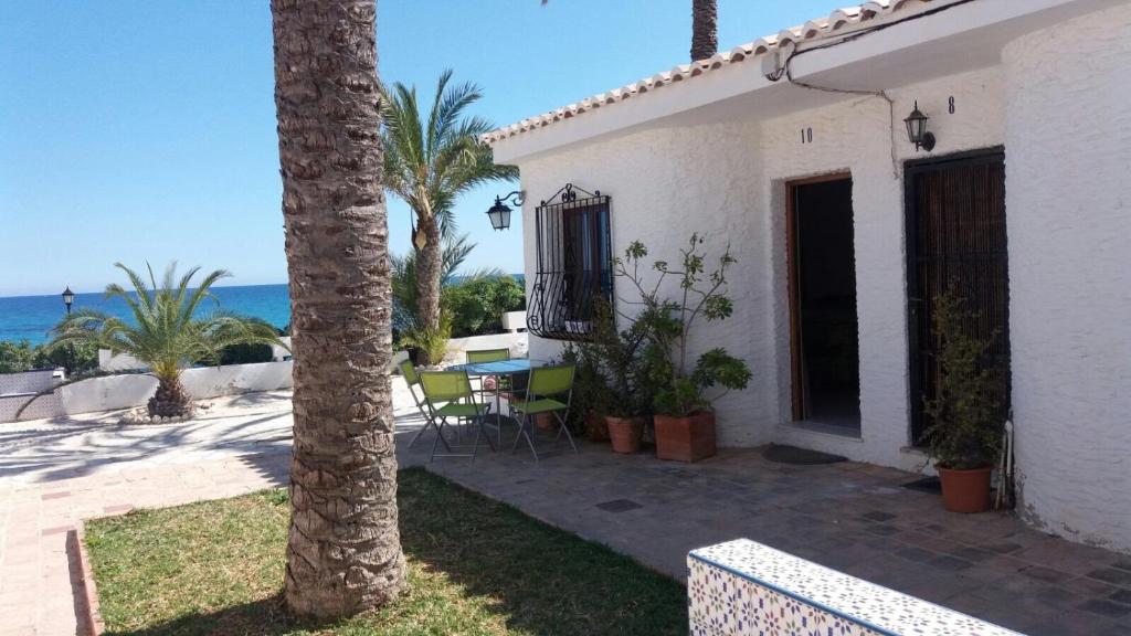 uma casa branca com uma mesa e uma palmeira em Casa al borde del mar em El Campello