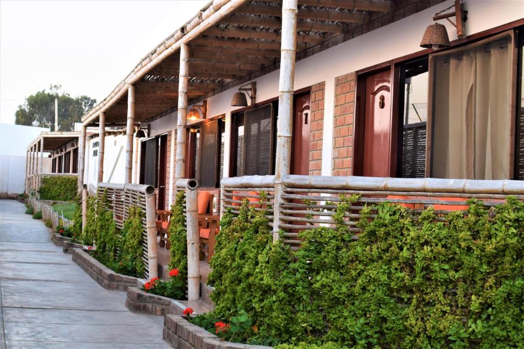 un edificio con una fila de plantas junto a una acera en Zarcillo Paradise, en Paracas