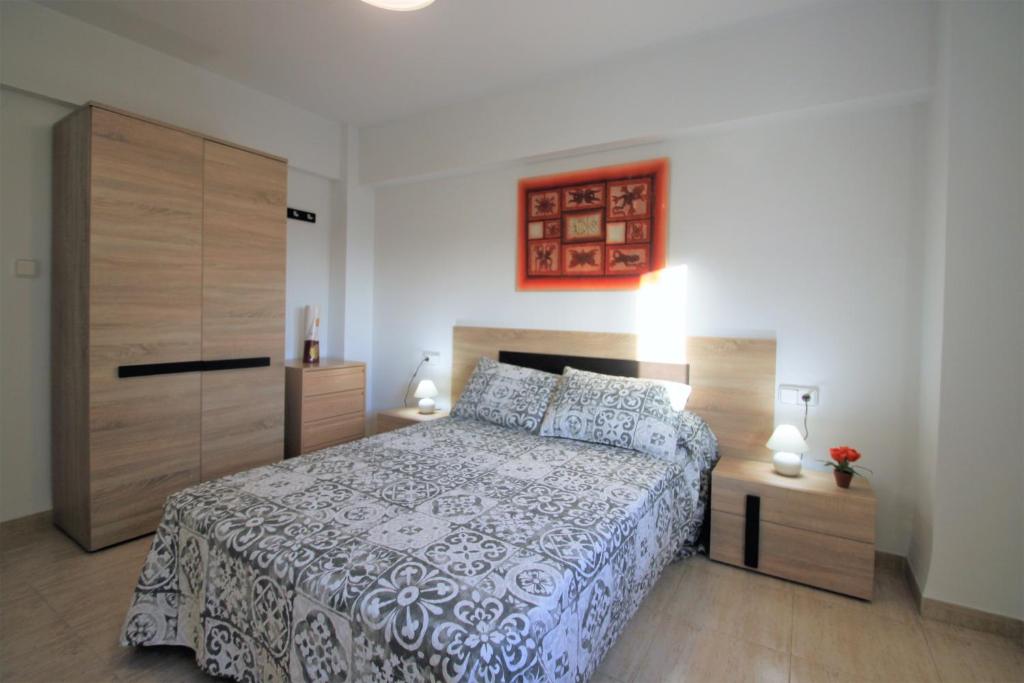 um quarto com uma cama e um armário de madeira em CasaTuris Playa Postiguet A113 em Alicante