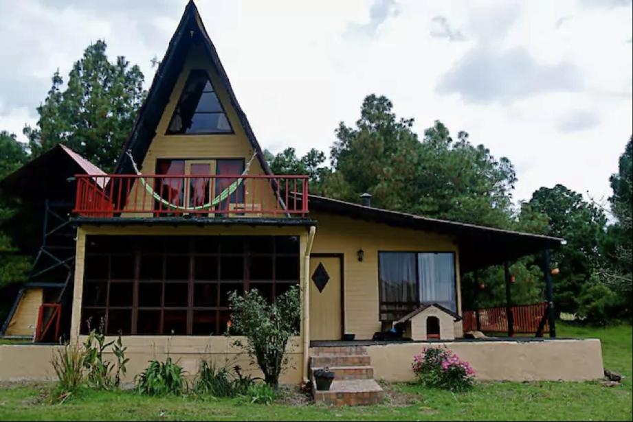 uma casa com uma varanda em cima em Chalets Amarelo em Suesca