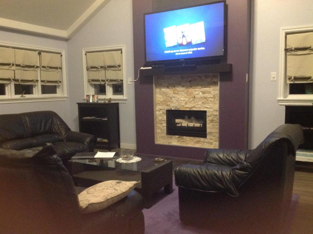 a living room with couches and a fireplace with a television at Pine Trees View Bungalow in Ottawa