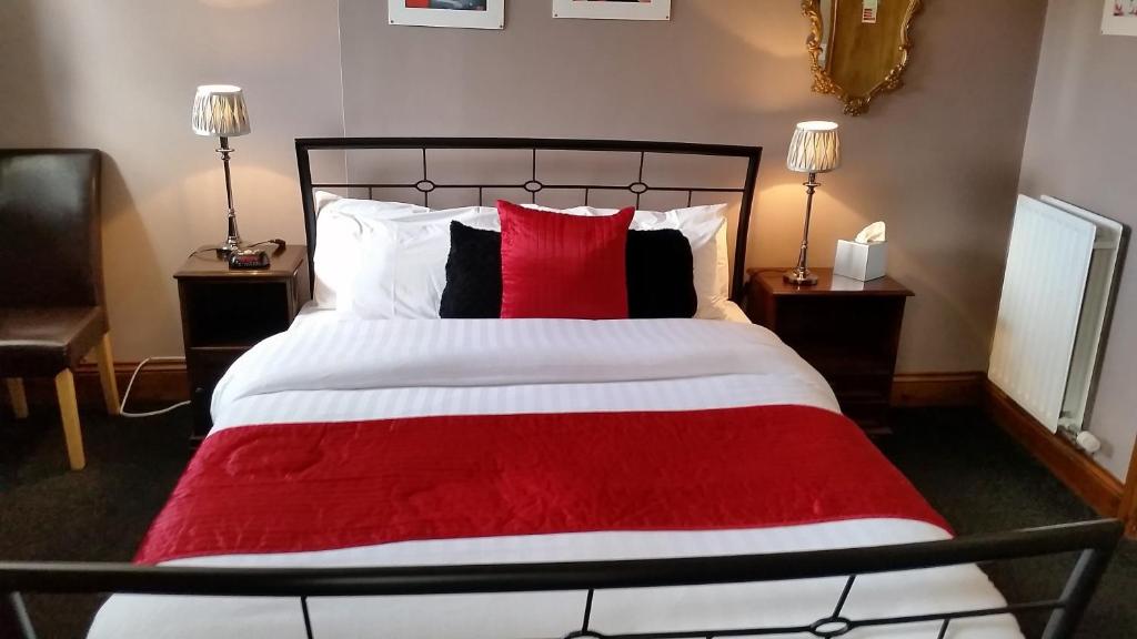 a bedroom with a large bed with red and white pillows at Forresters Bar & French Restaurant with Rooms in Middleton in Teesdale