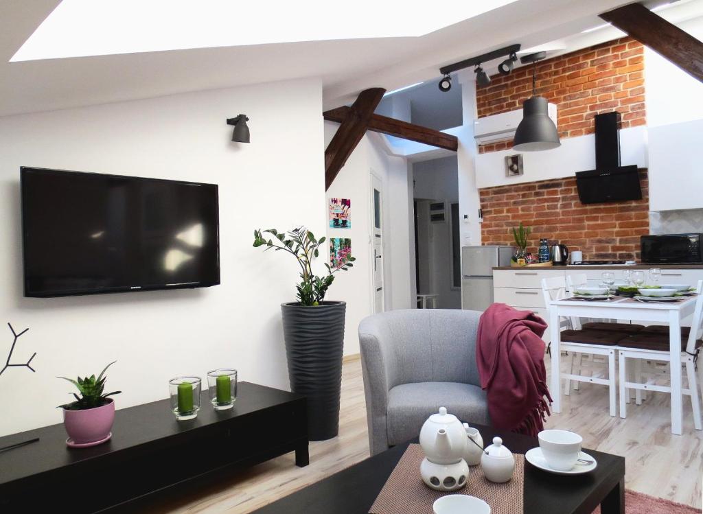 a living room with a couch and a tv on a wall at Apartament krakowski GIMO na Kazimierzu in Krakow