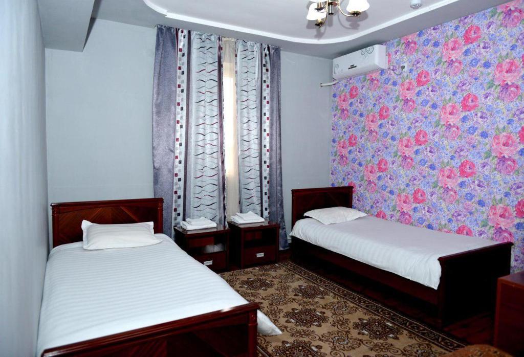 two beds in a small room with floral wallpaper at Carat Hotel in Tashkent