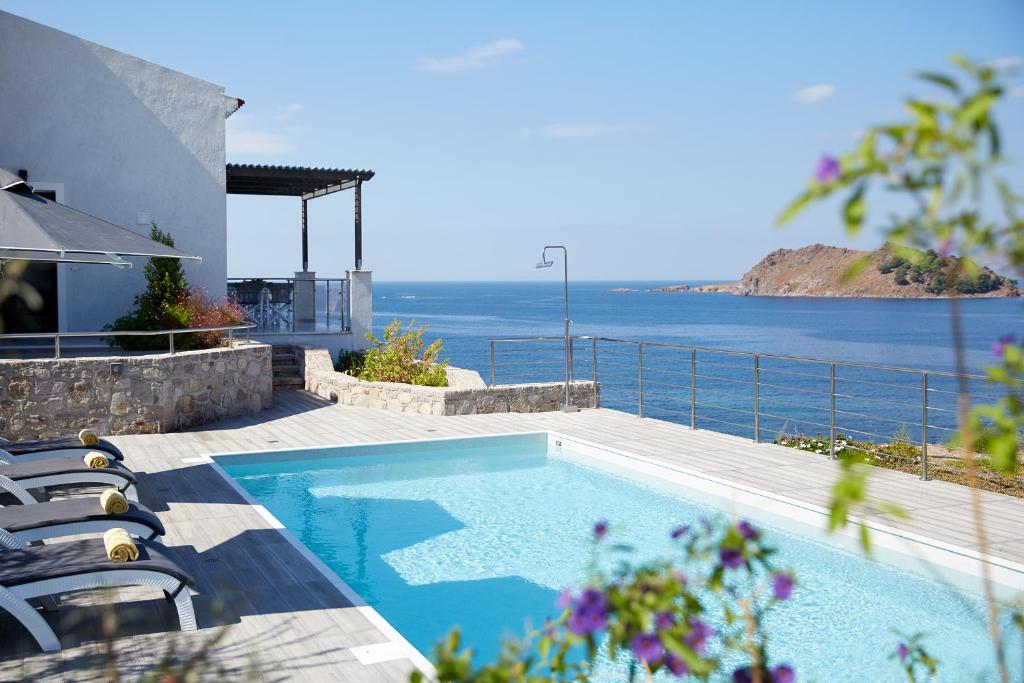 einen Pool mit Stühlen und Meerblick in der Unterkunft Eleia Seafront Rooms & Villas in Petra