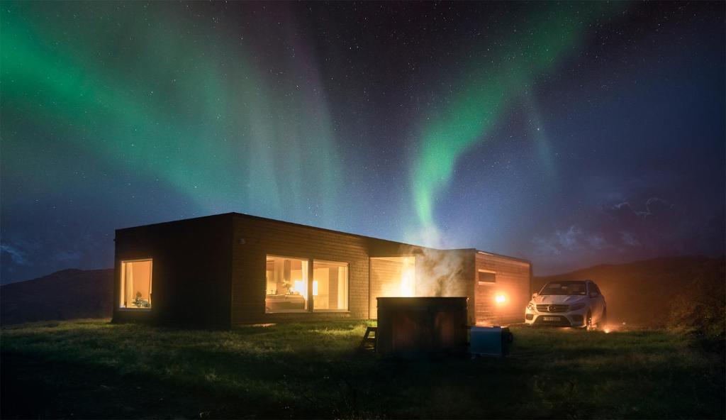 a house with a car parked next to it under the northern lights at Hrifunes Nature Park in Hrífunes 
