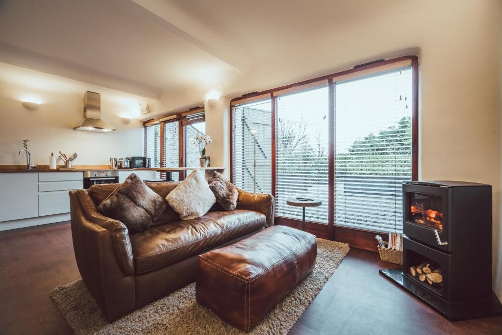 a living room with a leather couch and a fireplace at The Little Fish in Cockermouth