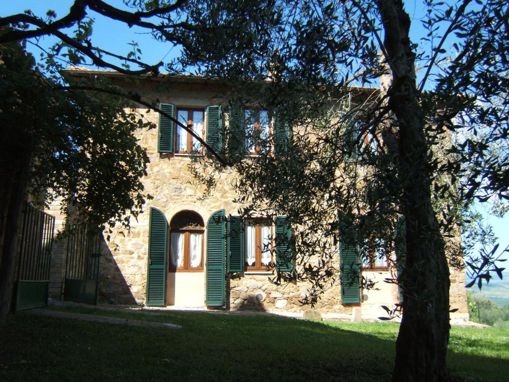 una casa de piedra con persianas verdes y un árbol en Villa Santa Maria, en Montalcino