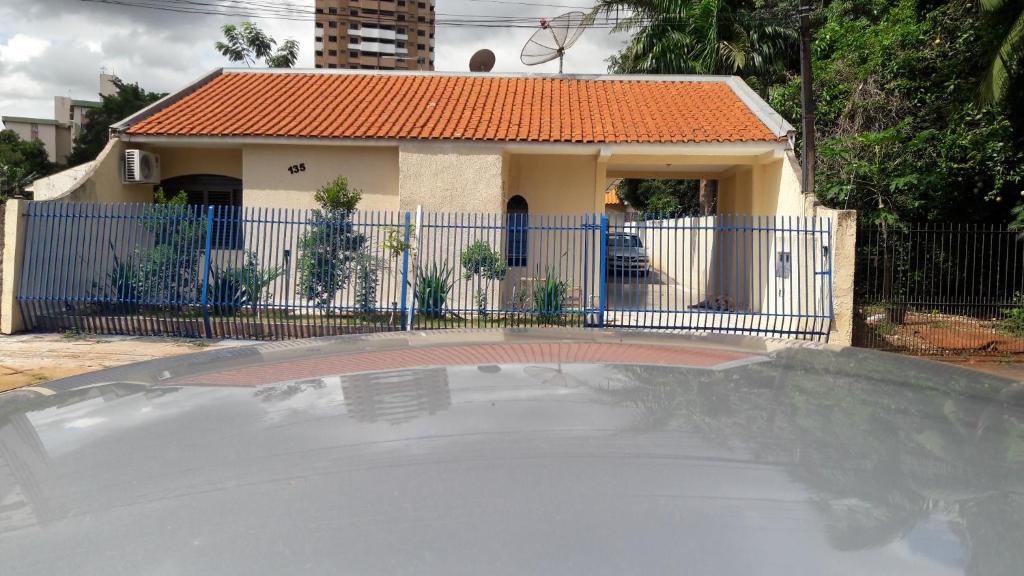 mały dom z niebieskim płotem i boiskiem do koszykówki w obiekcie Pousada Catarina w mieście Maringá