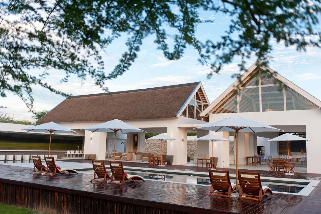 ein Haus mit Stühlen und Sonnenschirmen auf einer Terrasse in der Unterkunft Emanya@Etosha in Fort Namutoni