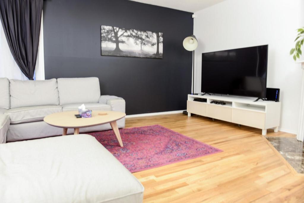 JstLikeHome - Getaway في أوتاوا: غرفة معيشة مع أريكة بيضاء وتلفزيون