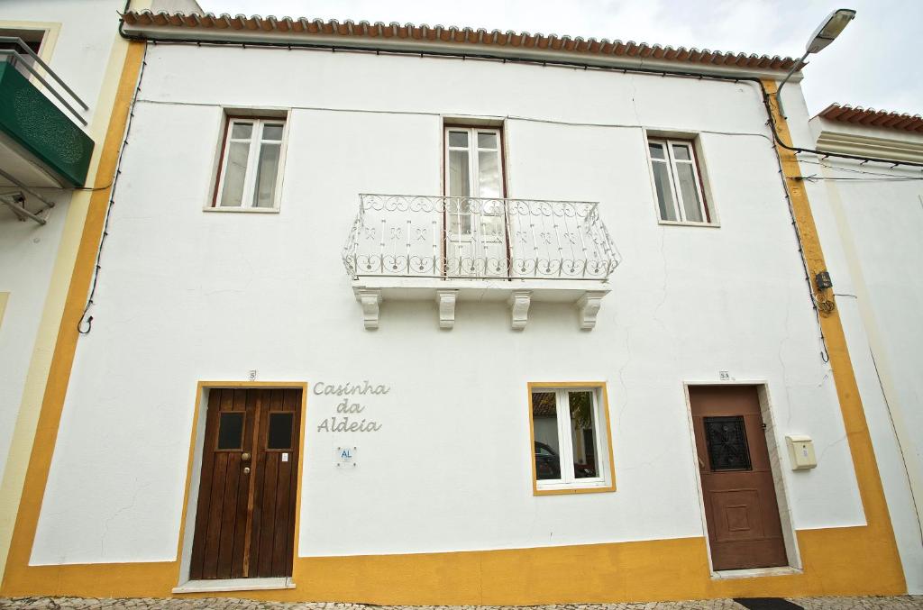 una casa bianca con un balcone sul lato di Casinha da Aldeia a Melides