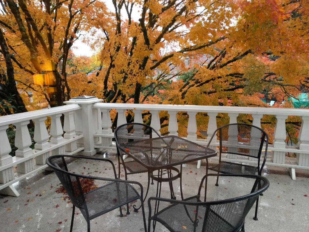 three chairs and a table on a porch with trees at Evermore Guesthouse in Portland